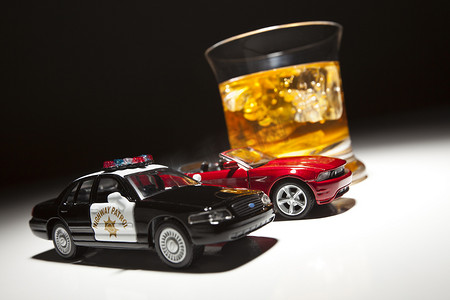 饮酒驾驶摄影照片_在酒精饮料旁边的警察和跑车