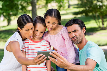 幸福的家庭在公园里用手机自拍