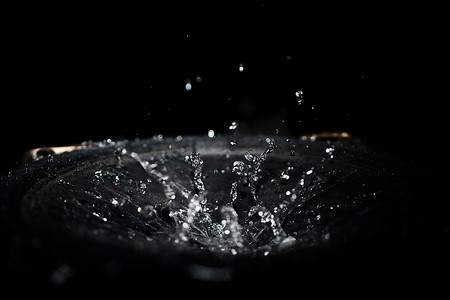 流动的水摄影照片_黑色背景上扬声器中的水滴飞溅。