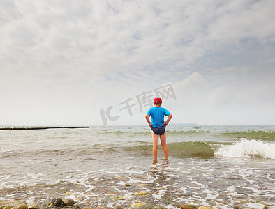 黑t恤的人摄影照片_海滩上的孩子们进入大海。