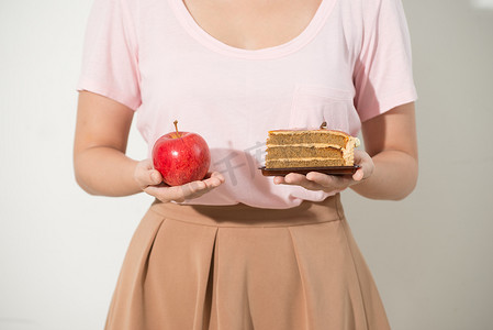 女孩一只手拿着苹果，另一只手拿着蛋糕。