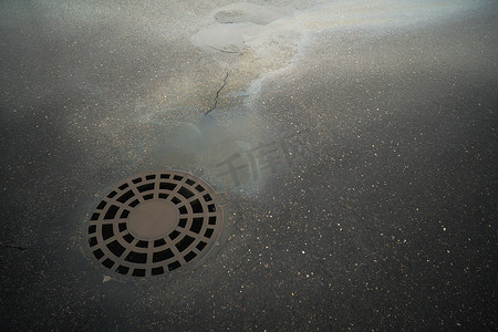 在柏油路背景的浮油排入雨水道