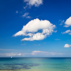 与蓝色多云天空和小风船的海洋风景