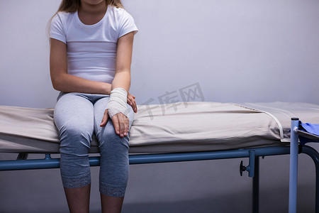 手受伤的女孩坐在担架床上