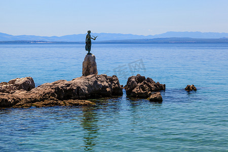 少女与海鸥的青铜雕塑，背景为 O 海