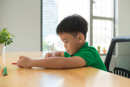 亚洲小男孩在家学习和做作业，在桌上，家庭教育，思考行动