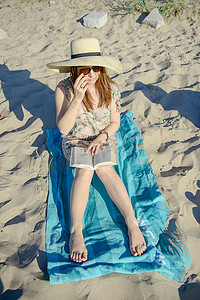 书的海洋摄影照片_一个年轻的黑发女人在沙滩上放松、看书的画像