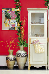 圣诞节花瓶摄影照片_在红色墙壁上的圣诞节装饰有花瓶和抽屉的
