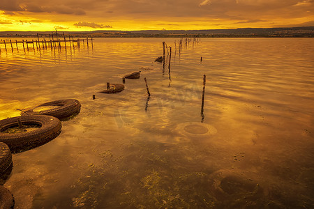 滴血的匕首摄影照片_湖上五颜六色的夕阳，水中有渔网，旧轮胎