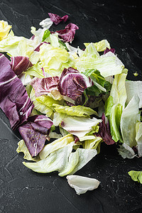 在黑石背景中混合芝麻菜、生菜、菠菜、沙拉用甜菜的新鲜叶子