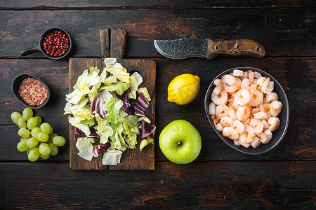 全鲜生虾去皮煮华尔道夫虾沙拉，配酱苹果和葡萄，放在旧的深色木桌上，俯视平躺