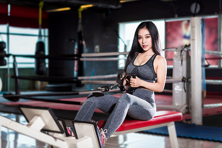 rows摄影照片_健身亚洲女性在运动健身房内部和健身健身俱乐部使用划船机（Seat Cable Rows Machine）进行锻炼训练，并配有运动健身器材健身房背景。