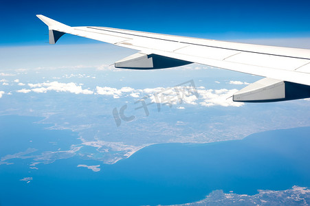 飞机高空摄影照片_从高空多云的天空和地中海海岸线的机载飞机窗口查看。