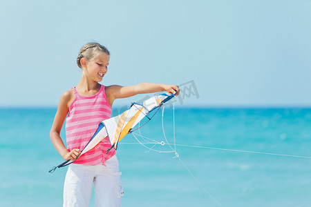 沙滩上玩彩色风筝的可爱女孩