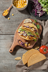 有地肉摄影照片_传统的墨西哥炸玉米饼，木桌上有鸡肉和蔬菜。