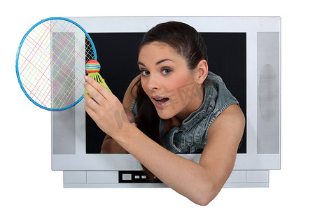 可爱羽毛球摄影照片_拿着羽毛球拍逃离电视的女人