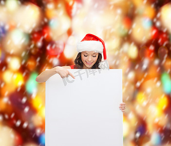 带帽的女人摄影照片_带空白白板的圣诞老人助手帽的女人