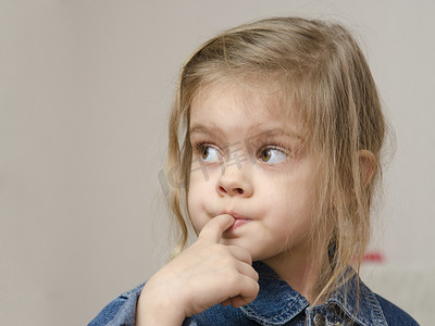 毛发粗浓杂乱的摄影照片_四岁女孩嘴里含着手指向左看