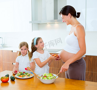 美丽的怀孕母亲和她的女儿们在厨房