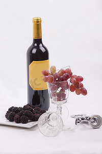 红色大气红酒摄影照片_一瓶红酒和装满葡萄的玻璃杯