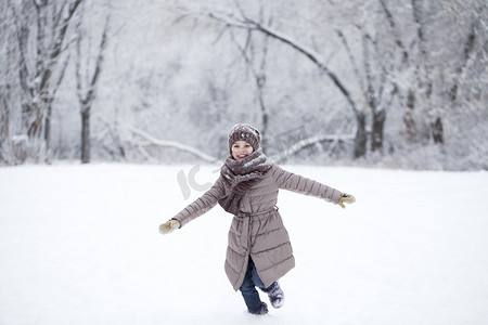 跑在积雪的冬天背景的愉快的小女孩