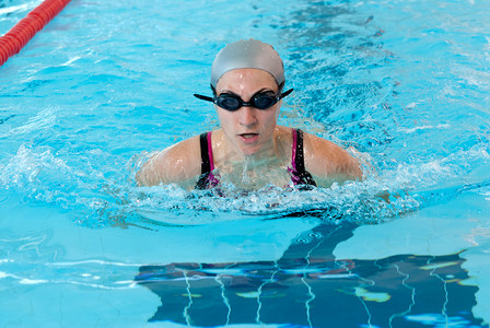 蛙泳运动员摄影照片_年轻女子在室内游泳池特写上游泳。