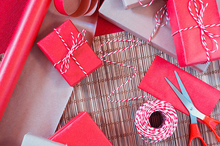 包装礼品摄影照片_为假期做准备-用红色和米色包装纸包装礼品