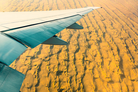 飞机机翼摄影照片_飞机机翼下的沙漠中的沙子。