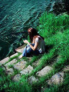 河岸摄影照片_坐在河岸上的年轻女子