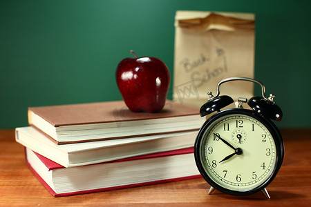 学校桌上的午餐、苹果、书籍和时钟