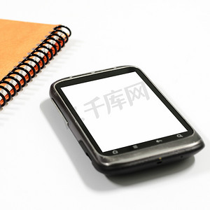 黑色桌子背景摄影照片_有笔记本的智能手机