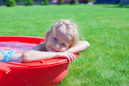 肖像迷人的小女孩在户外游泳池享受假期