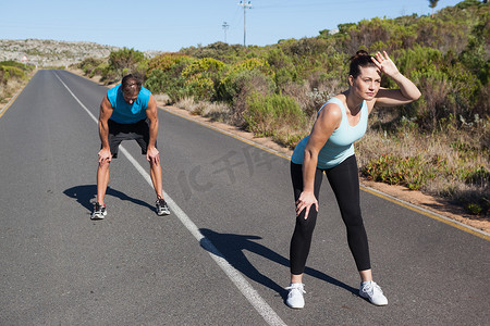 运动夫妇在开阔的道路上慢跑休息