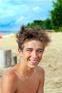 毛发粗浓杂乱的摄影照片_海滩上的少年
