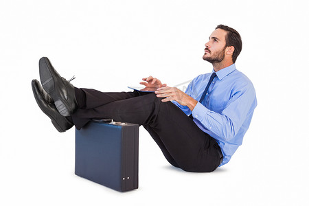 商人在使用他的平板电脑时双脚坐着