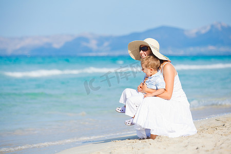 热带海摄影照片_年轻的母亲带着儿子去海滩度假