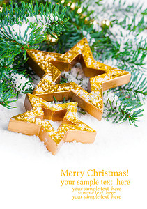 星点缀摄影照片_带松枝和雪的金色圣诞星，带免费空间