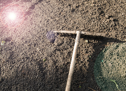 土壤阳光摄影照片_耕种黑土上的花园耙 — 园艺概念、园林春季工作、阳光