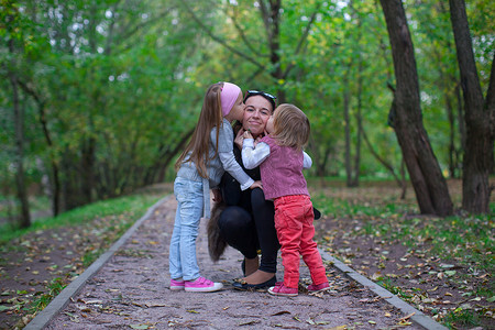 年轻快乐的父亲和他的女儿们在公园里玩得开心