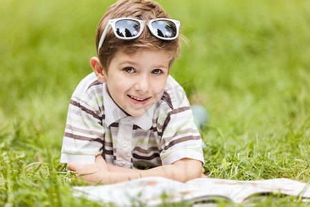 美丽微笑的儿童男孩在户外看书