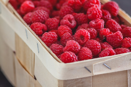 红色复古风摄影照片_深色复古风的篮子里放着鲜亮多汁的成熟红树莓