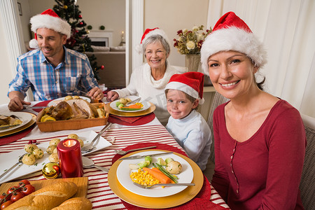 圣诞晚餐期间戴着圣诞帽的幸福家庭