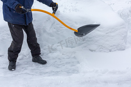 大雪过后，一个男人用铲子清理院子里的雪
