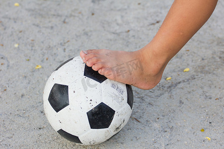 一个男孩在水泥地上踢足球的脚的特写