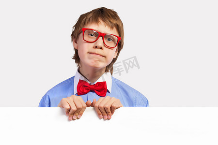 孩子的困惑摄影照片_拿着白方块的红色眼镜的小学生