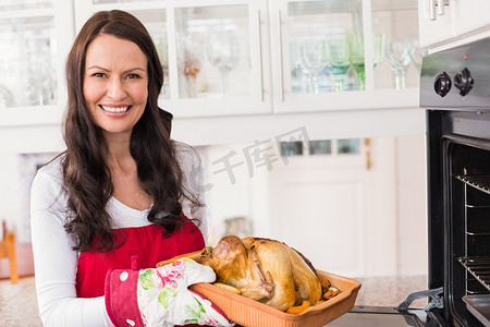 圣诞节火鸡摄影照片_拿着烤火鸡的微笑的女人