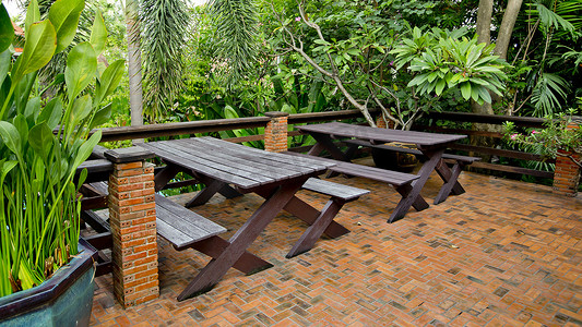 木椅和桌子摆放在绿色植物园的阳台上。
