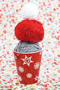 红花背景的灰色、红色和白色编织球和红色圣诞杯