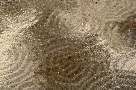 波形图摄影照片_多色调棕色沙子表面上的圆圈