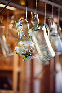 磨砂酒瓶摄影照片_挂在挂钩上的波西米亚玻璃酒瓶